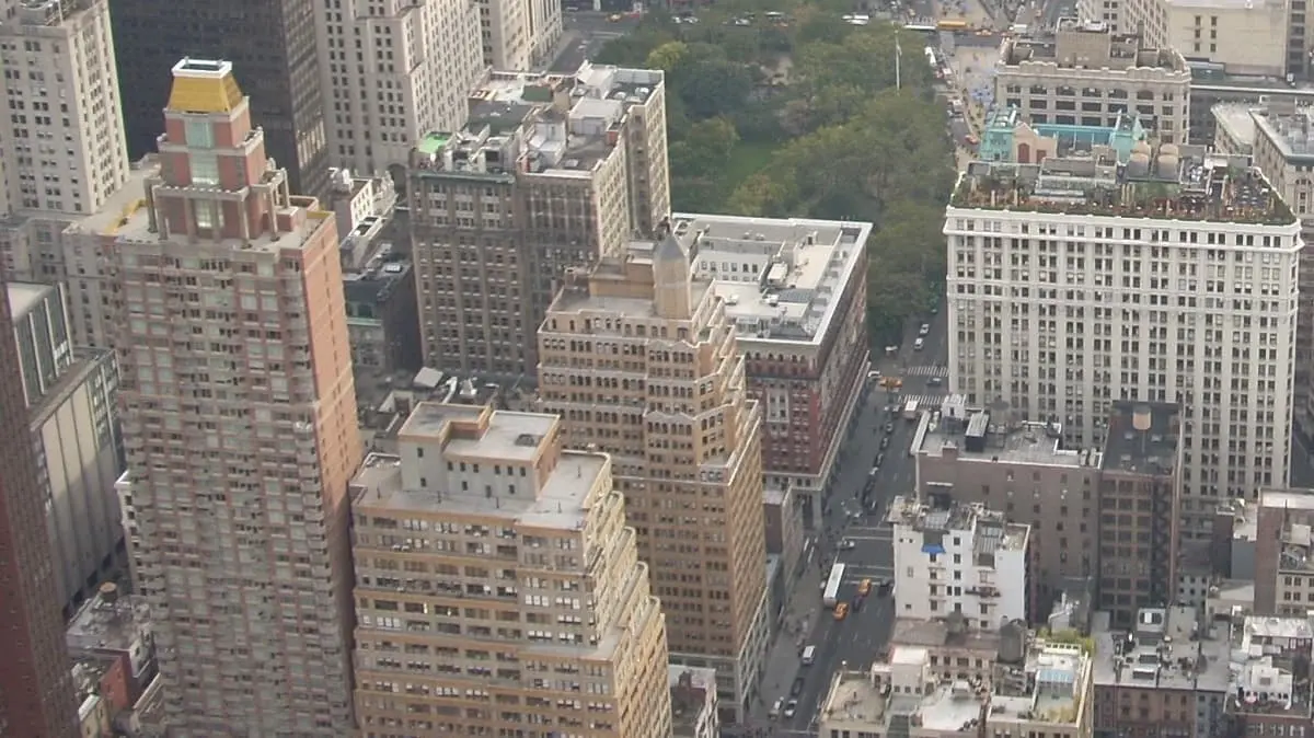 晴れた日のニューヨーク、ミッドタウン・マンハッタンの航空写真。多様な建築様式と高さの無数の高層ビルが建ち並び、一部には緑豊かな公園も見え、都市の密度と多様性を表している。