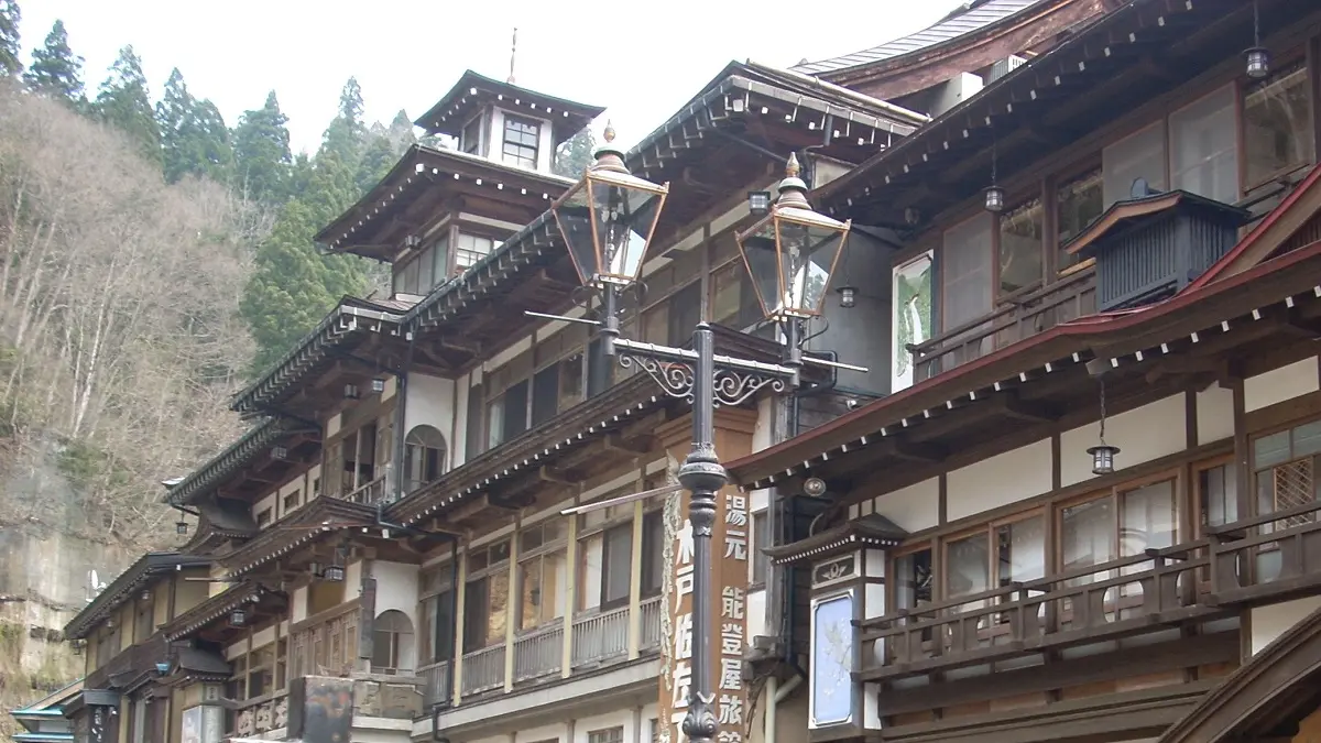 山間の静かな温泉街に佇む木造の旅館。重厚な木組みと障子窓が印象的で、舌切り雀の昔話に登場するような、どこか懐かしくも幻想的な雰囲気を醸し出している。