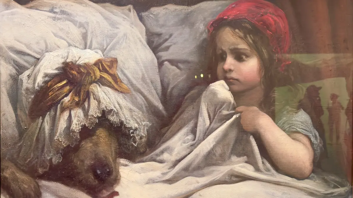 童話『赤ずきん』を描いた19世紀の油彩画。ベッドに横たわる狼（おばあさんの帽子を被っている）と、その隣で不安げな表情を浮かべ、シーツを握りしめる赤い頭巾を被った少女。